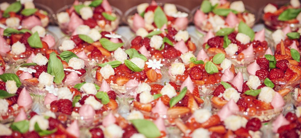 A close-up picture of dishes filled with fruit, cake pieces, and more for a dessert dish.