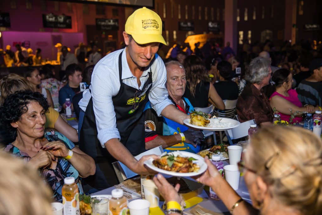 A person serving meals to the people sitting at the table.